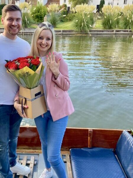 A couple of a traditional wooden punt after a proposal with flowers