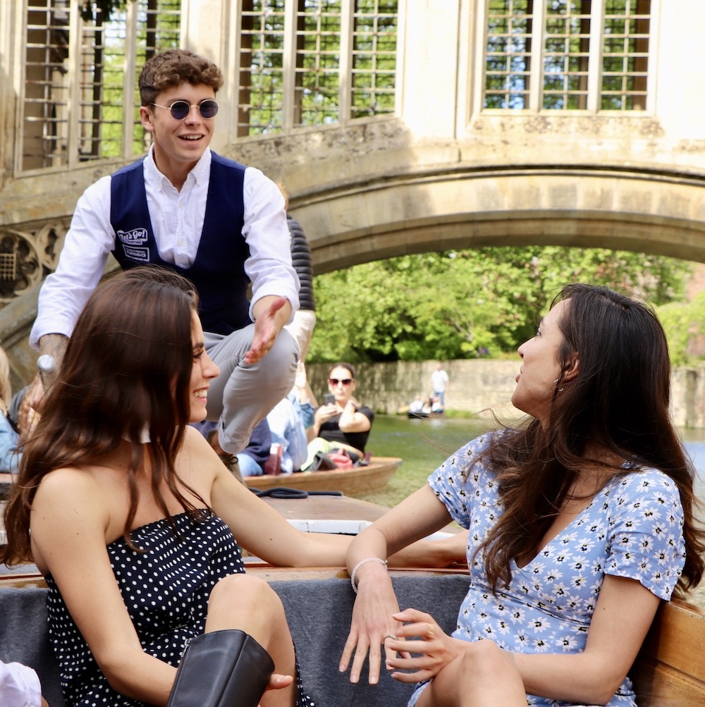 group of friends chatting to the punt chauffeur in front of the Bridge of Sighs in Cambridge
